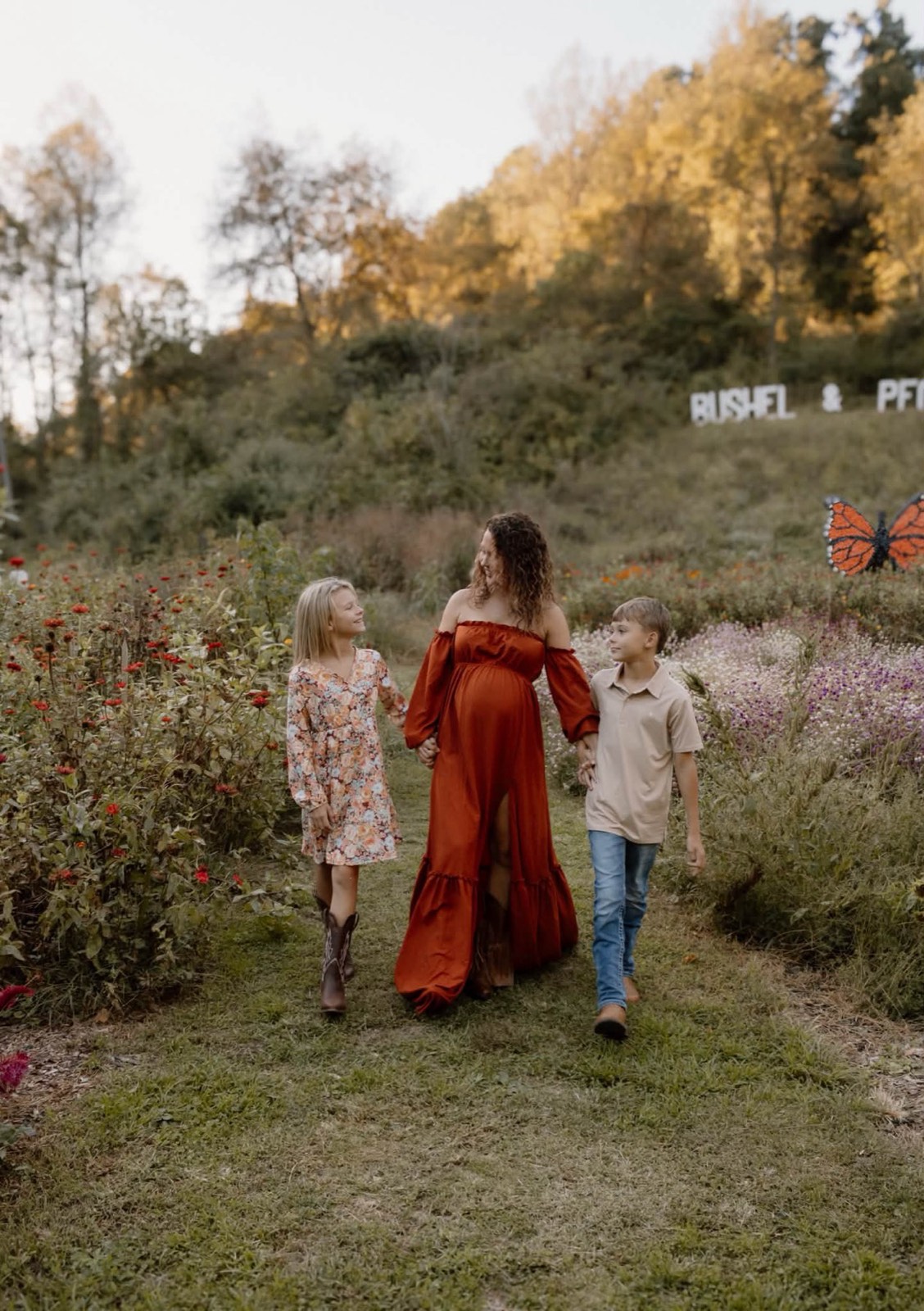 A pregnant mother walking through a flower field with her two children near Grayson, Kentucky.