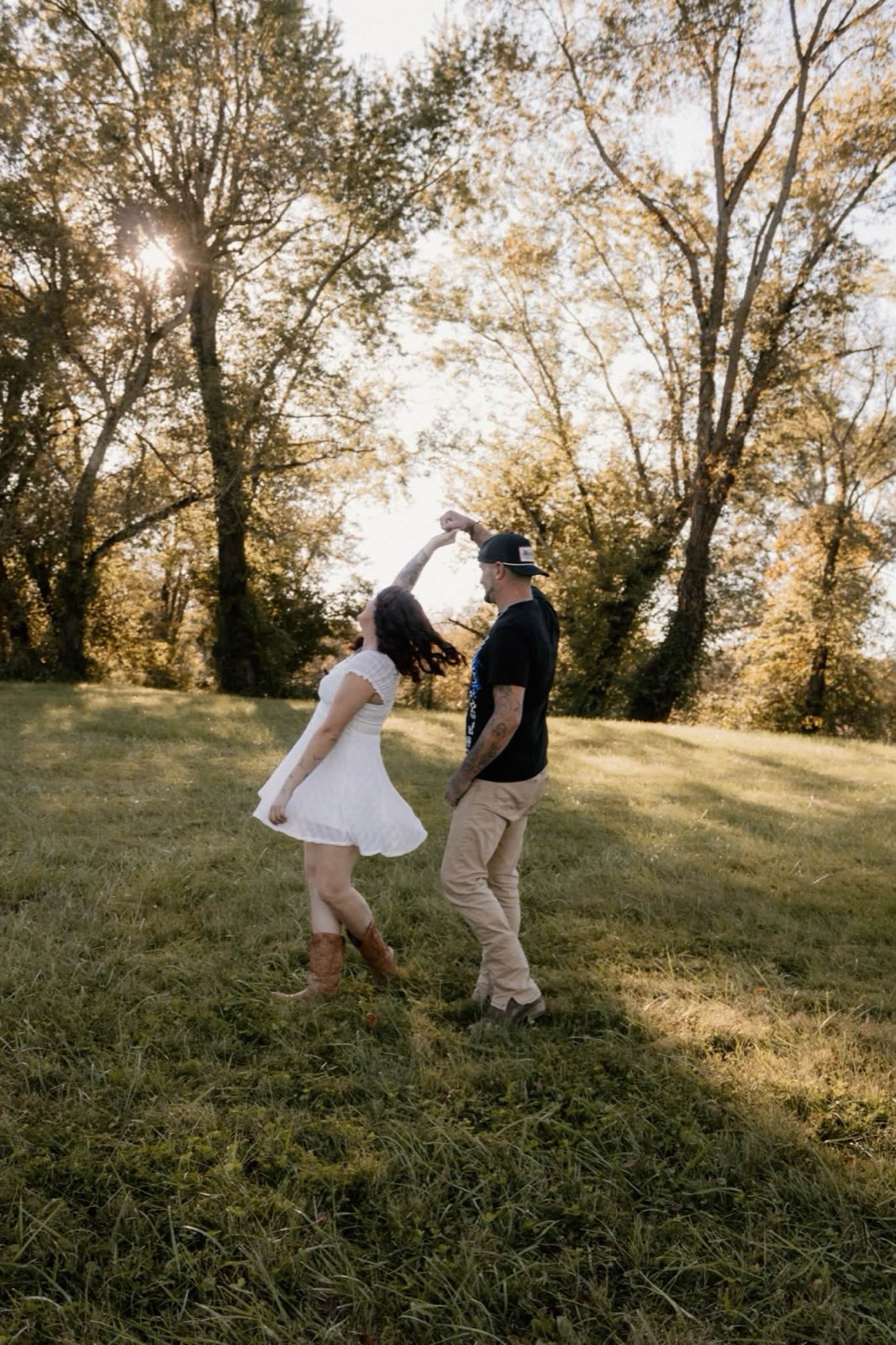 A couple dancing in a sunlit field near Grayson, Kentucky, photographed by Omens Photography.
