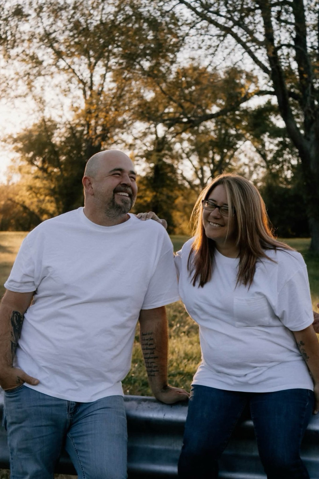 A couple in white shirts leaning on a guardrail in golden-hour light near Grayson.