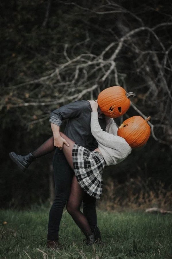 A couple in jack-o'-lantern heads during a Halloween portrait by Omens Photography.